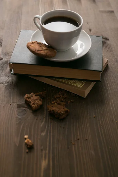 Kaffeetasse und Kekse liegen auf Bücherstapel — Stockfoto
