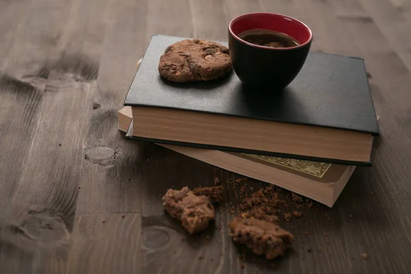 Kaffeetasse und Kekse liegen auf Bücherstapel — Stockfoto