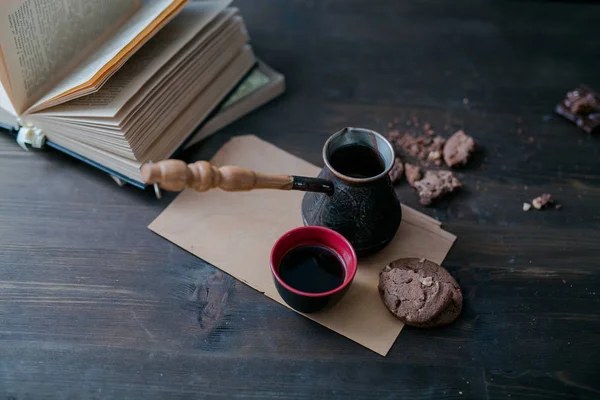 Kaffeetasse und Kekse und Kaffeemaschine liegen auf dem Holztisch neben dem Buch — Stockfoto
