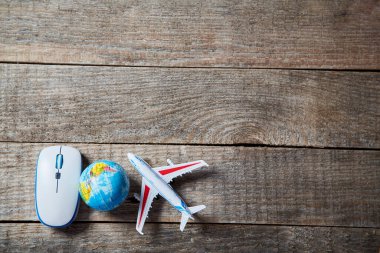 İnternetten bilet ayırtıyorum. Uçakta uzaktan kontrol var. Seyahat yönünü seçiyorum. Teknoloji ve dünya turu konsepti. Bilgisayar faresi ve dünya küresi ahşap arkaplanda kopyalama alanı ile