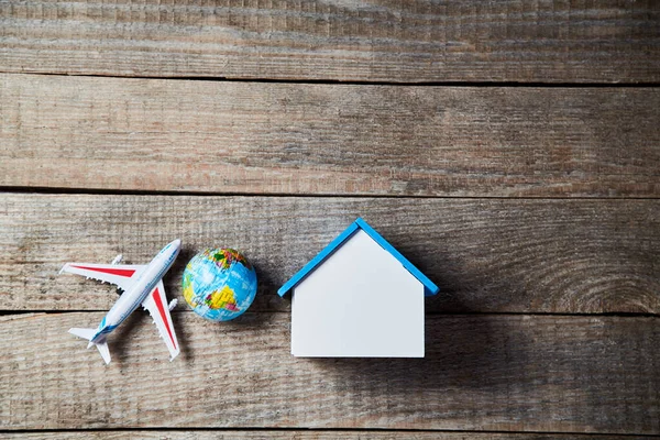 Planejando viajar. Transporte aéreo. Casa alugada. Viagem à volta do mundo. Conceito de férias e viagem. Miniatura de home mockup com espaço de cópia, globo terrestre e brinquedo de avião. Fundo de madeira — Fotografia de Stock