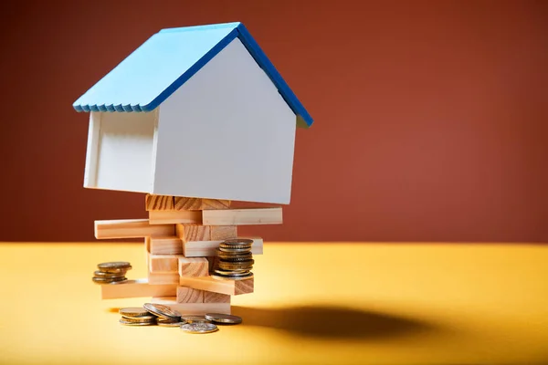 Emlak piyasasında belirsizlik ve riskler. Para ve ev modeli ahşap tuğlalarda. Taşınmaz emlak yatırımı