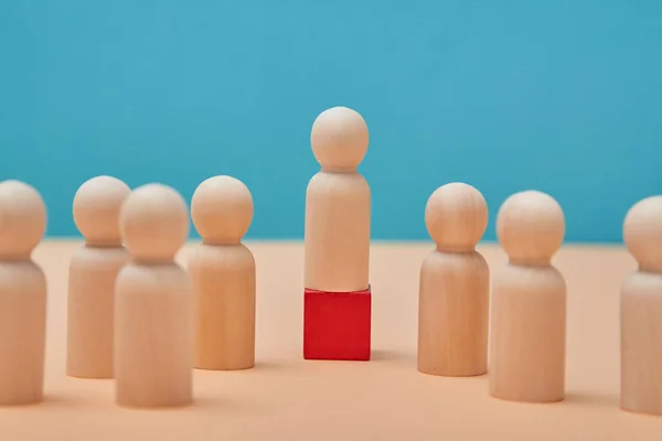 Ledarskap i laget. Individualitet och överlägsenhet. Leader figur sticker ut från mängden på röd trä kub, underordnade — Stockfoto