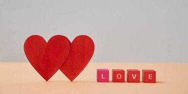 Aşk ve sevgi. Sevgililer Günü. Aşk ve ilişki. İki kırmızı kalp, üzerinde aşk yazıları olan tahta küpler.