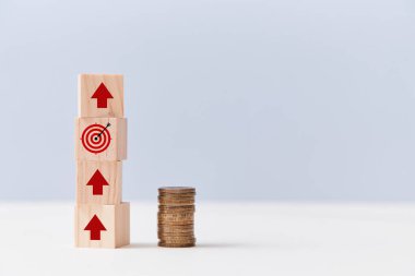Finansal büyüme. Gol başarısı. Gelir artışı. Tahta küpler, oklar, hedef işareti, bozuk para yığını.