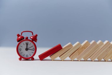 Süre kısıtlı. Zaman ve süre kısıtlı. Domino etkisi. Kırmızı alarm saati ve tahta blok, kopyalama alanı. Zaman tükeniyor.