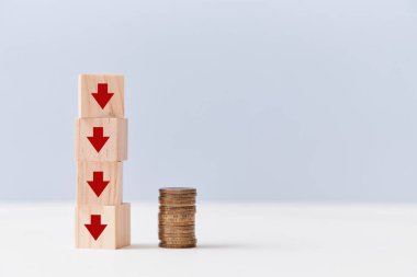 Finansal kriz. Gelir azalıyor. İflas, parasızlık. Tahta küpler üst üste, oklar aşağı ve bozuk para yığını