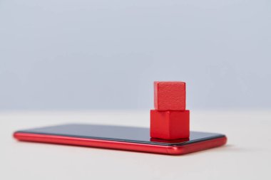 Modern akıllı telefon modelinde kırmızı tahta küpler. Cep telefonu şablonundaki boş bloklar. Mobil internet, hizmetler, kopyalama alanı