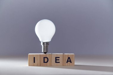 Yeni fikir üretimi. İçgörü ve yaratıcı düşünce. Mükemmel bir fikir. Üzerinde yazı ve ampul olan tahta küpler.