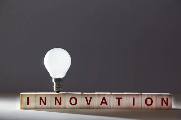 Innovationsideen. Kreative Einsicht. Originelles Denken und Kreativität. Holzwürfel, Glühbirne auf dunklem Hintergrund — Stockfoto