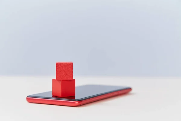 Internet móvil, servicios, espacio para copias. Cubos de madera roja en la maqueta moderna smartphone. Bloques en blanco en la plantilla de teléfono celular . —  Fotos de Stock