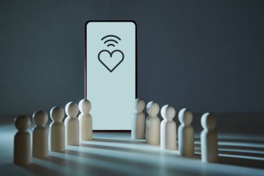 İnternetten randevulaşma. Sanal iletişim için internet uygulaması, kopyalama alanı. Kalp, wifi, akıllı telefon ekranı, ahşap figürler.