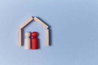 - Aile. Sevgi dolu bir çift. Evlat edinme ve ilişki kavramı. Tahta figür evde. Uzayı kopyala Mavi arkaplanda izole edilmiş