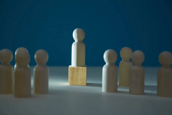 Träfiguren står på kuben. Människor miniatyr och ledare på mörk skugga bakgrund. Ledarskap och överlägsenhet — Stockfoto