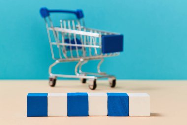 Yaratıcı tasarım ve yazıtlar için sıralanmış tahta küpler. Bulanık arka planda alışveriş arabasının şablonu. Boşluğu kopyala