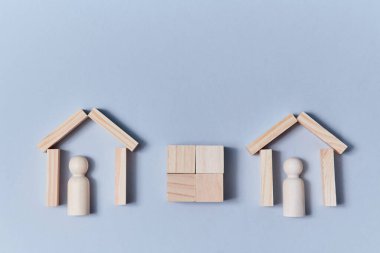 Binalar arasında boş küp. İçinde boş insan figürleri olan ahşap kalaslardan evler. Uzayı kopyala Mavi üzerine izole edilmiş.