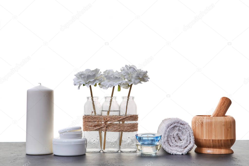 Wooden mortar tubes with cream. Candles and white towel. Aromatic oils. Spa day. Skincare. White backdrop. Copy space