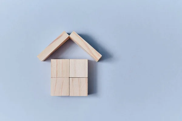 Dřevěné kostky pod střechou domu z dřevěných prken, kopírovací prostor. Mockup styl pro kreativní design. Izolováno na modrém pozadí — Stock fotografie