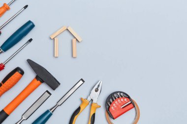 Bina binası. Yenileme konsepti. Bloklardan yapılmış ev minyatürü. Mavi arka planda bir takım enstrümanlar. Boşluğu kopyala