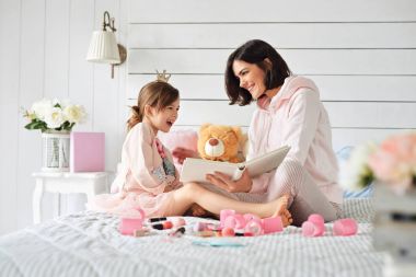 Anne kızına bir kitaptan bir şeyler gösteriyor