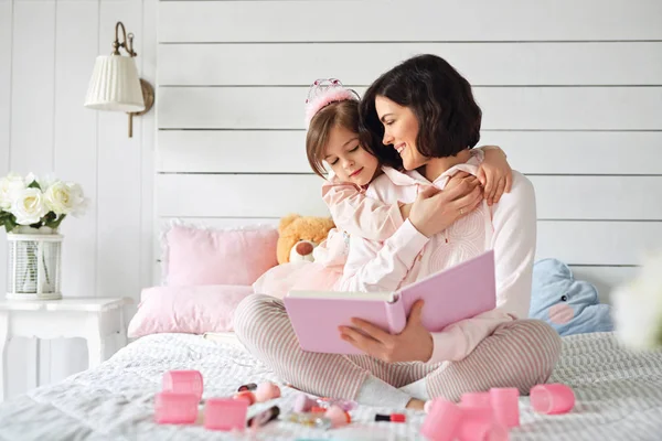 Little girl is hanging on her mothers neck