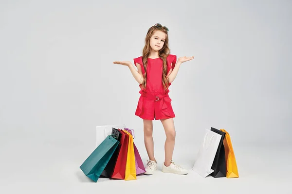 Маленькая девочка стоит вокруг сумки покупателей — стоковое фото