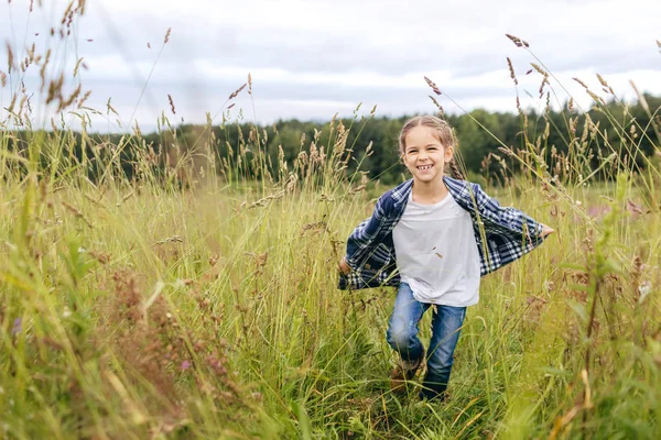 Pequena menina adorável correndo no prado, tendo expressão feliz enquanto desfruta de bela natureza. Menina encantadora correndo na grama verde, se divertindo sozinho. Infância, estilo de vida, conceito de relaxamento — Fotografia de Stock