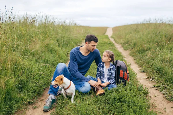Sevgi dolu baba kızı hoş konuşmayı onunla dakika sonra uzun bir yürüyüş için onların köpek ile dinlenme, yakın oturan. Baba, kızı ve yeşil yol dışında oturan köpek — Stok fotoğraf