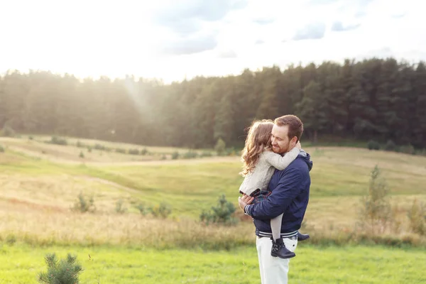 Pessoas, relacionamento, família, conceito de felicidade. Pai feliz carregando sua filhinha, sentindo união e amor enquanto caminhava no prado verde. Pai alegre e seu filho pequeno bonito — Fotografia de Stock