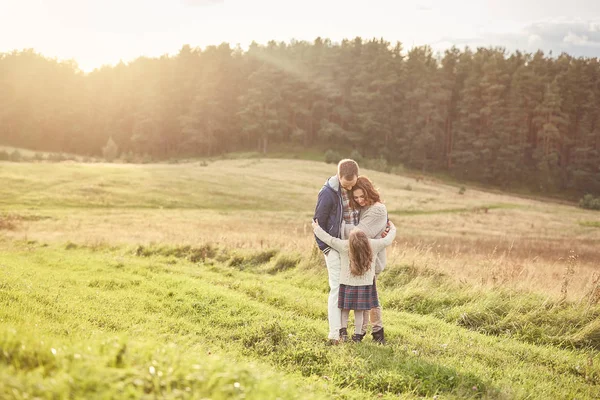 Familie, Harmonie, Beziehungskonzept. freundliche Familie, die sich umarmt, gute Beziehungen unterhält, sich im Freien ausruht, Zusammengehörigkeit spürt, während man in der Natur ist. junges Paar und ihre kleine Tochter — Stockfoto