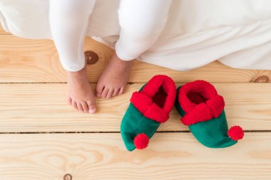 Çocuk s çıplak ayak kapalı atış, elf s ayakkabı yakınındaki ahşap zemin üzerinde duruyor yürüyüş olacak erken sabah, uyanır. Tanınmayan çocuk fotoğrafı. Alışılmadık magestic Ayakkabı.