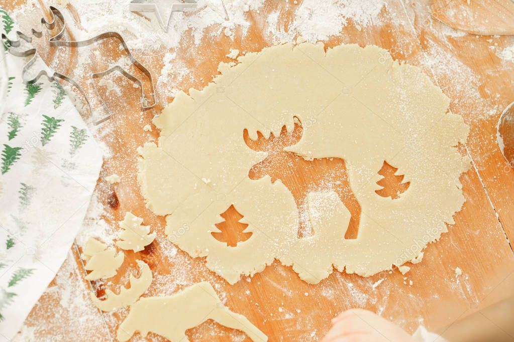 Deer and New Year tree cut on dough, Ready cookies of different shapes lie on wooden table, going to be baked. Hand made delicious pastry. Christmas cookies.