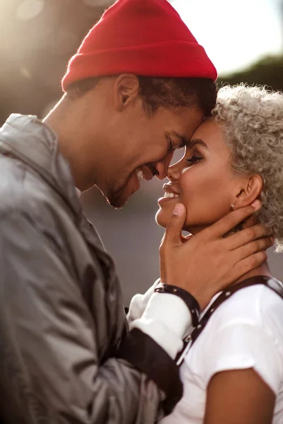 Vertical close up portrait of happy peased people in love being of different nation, express their good relationship and feelings. Dark skinned male in trendy hat looks sincerely in girlfriend s eyes. — Stock Photo, Image