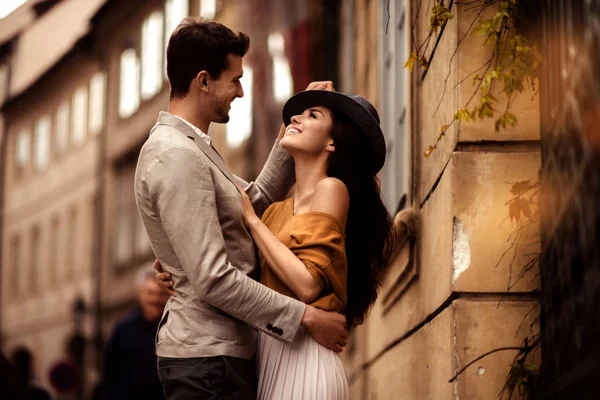 Vášnivé nádherný mladý pár objali během chůze přes starobylé město. Veselá elegantní roztomilá modelka nosí stylový klobouk, vypadá s veselým výrazem v očích s přítelem. — Stock fotografie