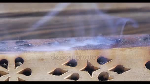 Hermoso humo de aroma cerca de la estatuilla. Figura uddha en madera tablero de té Chaban con un humo de aroma. Macro Primer plano de quemar palos de incienso con humo sobre fondo marrón. Palo de incienso ardiente — Vídeos de Stock