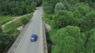 Arabanın hava anket ile serpantin üzerinde gidiyor. Uçan kırmızı cabriolet sürücü caddenin üzerinde. Köprünün diğer tarafında gider kırmızı araba hava görünümünü. Köprüde trafik. Kırmızı araba.