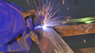 Metal kaynak kıvılcım ve duman ile. İşçi kaynak metal koruyucu maske ile. Kaynakçı metal parçalar katılır. Bir yarı otomatik kaynak kullanan işlem. Kaynak çelik. Fabrikada sanayi işçisi