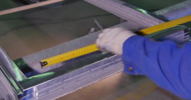 Kesmeden önce genişliğini emin olmak için bir bölüm ölçme bir adam. bir alt çerçeve penceresi için ölçer. Sac üzerinde işaretler yapmak için bir iletki ile çalışan. Şerit metre. İş