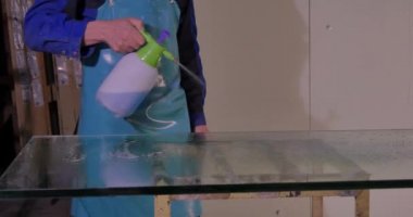 İşçi temiz ve kuru cam imalatı. Orta yetişkin çalışan temizlik sabun sud cam pencere üzerinde çekçek ile gülümseyen. Çalışan yıkama pencere stand büyük bardak. Su alt temiz cam kullanarak