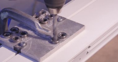 Alüminyum ve metal elektrikli matkap kullanarak delinmiştir delik. Alüminyum veya metal metal atölyesinde closeup elektrikli matkapla Delme. Yassı çelik plaka Delme tezgah matkap ile çalışan