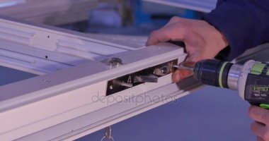İşçi montaj Pvc kapı ve pencere. İmalat işleri. Seçici odak. Alüminyum ve Pvc pencere ve kapı üretimi için fabrika. Delikli metal plaka mobilya vida ve fındık. İşçiler