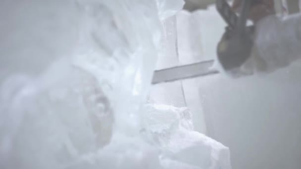 氷の彫刻の彫刻家のビュー。運動。チェーンソーで氷をカットします。カットし、氷の彫刻を作る。斧で氷を割ってください。氷の彫刻彫り。チェーンソーと雪。マスター、氷から氷の彫刻 — ストック動画