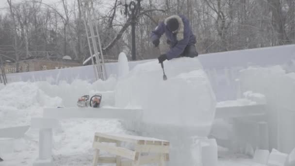 Master schraper voert een beweging over het ijs maken een ijssculptuur. Master met behulp van speciale gereedschap te slijpen naar beneden formulier ijs stukken. Ijs composities voert inkepingen en groeven In het stuk van — Stockvideo