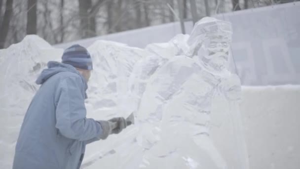 El rascador maestro realiza un movimiento a través del hielo para crear una escultura de hielo. Maestro utilizando la herramienta especial para moler abajo forma piezas de hielo. Composiciones de hielo realiza muescas y surcos en el pedazo de — Vídeo de stock