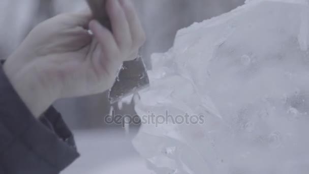 El rascador maestro realiza un movimiento a través del hielo para crear una escultura de hielo. Maestro utilizando la herramienta especial para moler abajo forma piezas de hielo. Composiciones de hielo realiza muescas y surcos en el pedazo de — Vídeo de stock