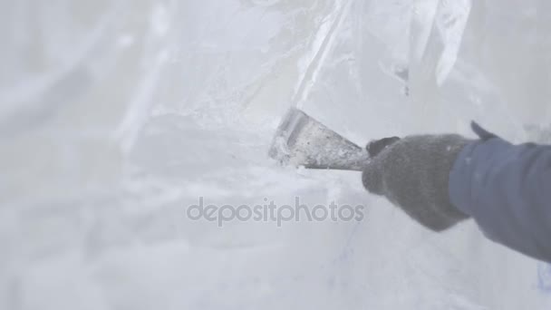 El rascador maestro realiza un movimiento a través del hielo para crear una escultura de hielo. Maestro utilizando la herramienta especial para moler abajo forma piezas de hielo. Composiciones de hielo realiza muescas y surcos en el pedazo de — Vídeo de stock