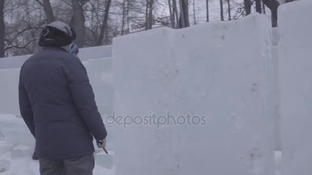 A desenhar na neve. Preparar para cortar o gelo. Esteja preparado para começar a fazer escultura de gelo. Para pintar a neve. Desenhe na neve usando a cor. Desenhe imagens na neve branca do inverno. V-LOG — Vídeo de Stock