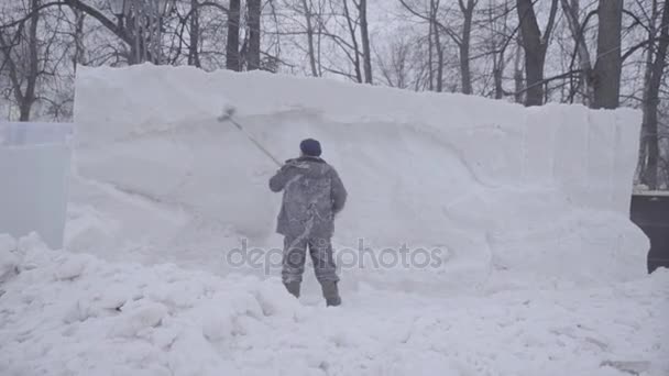 Man Shoveling Snow. Faça escultura feita de neve. Escultura de neve, blocos empilhados à espera de escultura. Esculturas de neve de animais em iluminação artificial. Homem com pá de neve limpa calçadas em — Vídeo de Stock