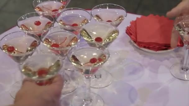 Lidé se od stolu sklenici Martini a whiskey. Champagne v brýlích s čerstvých cherry na stůl a strany pozadí. Pohled shora brýle s různých alkoholických nápojů na stůl na svatbě — Stock video