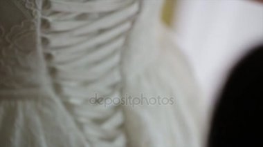 Günaydın gelin. Baş nedime geline elbisesinde yardım ediyor. Gelinler elbiseyi bağlar. Nedime gelinliği bağlıyor. Kadın eli, gelinlerin korsesine ipek kurdele bağlar. Bağcıkları bağlamama yardım et.